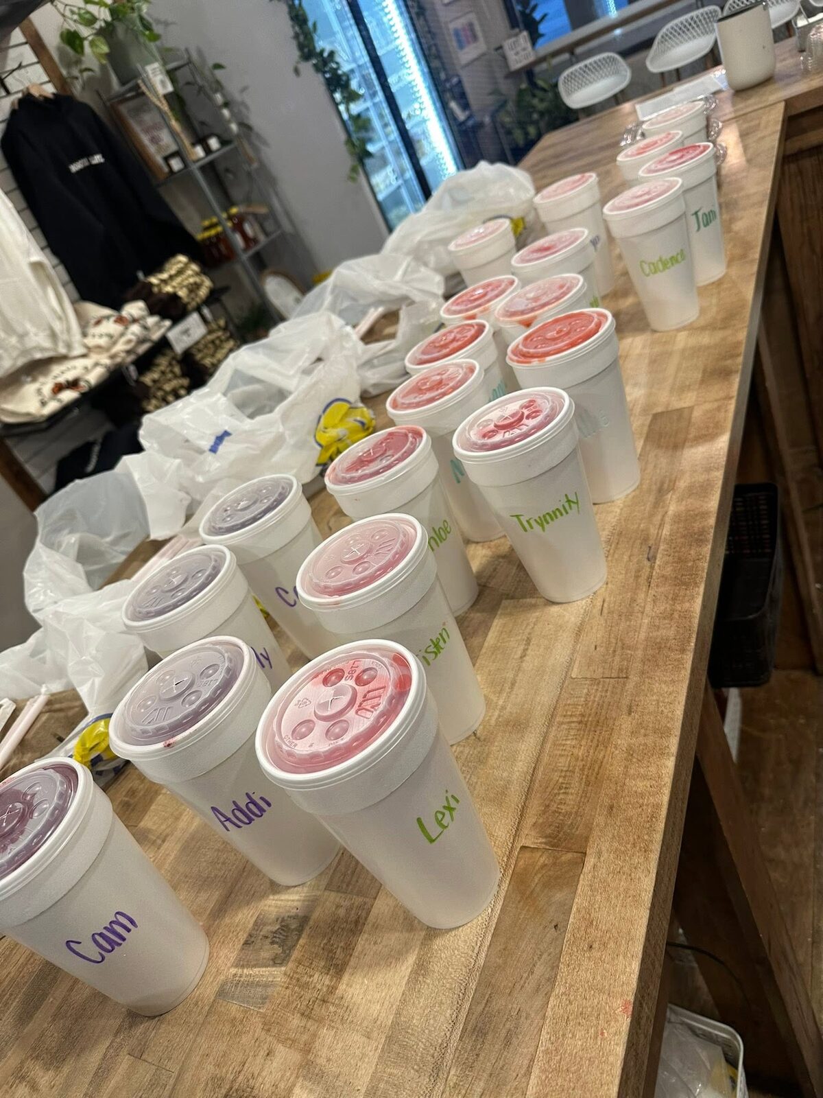 Smoothie cups with customers' names written on the lids, lined up on the counter