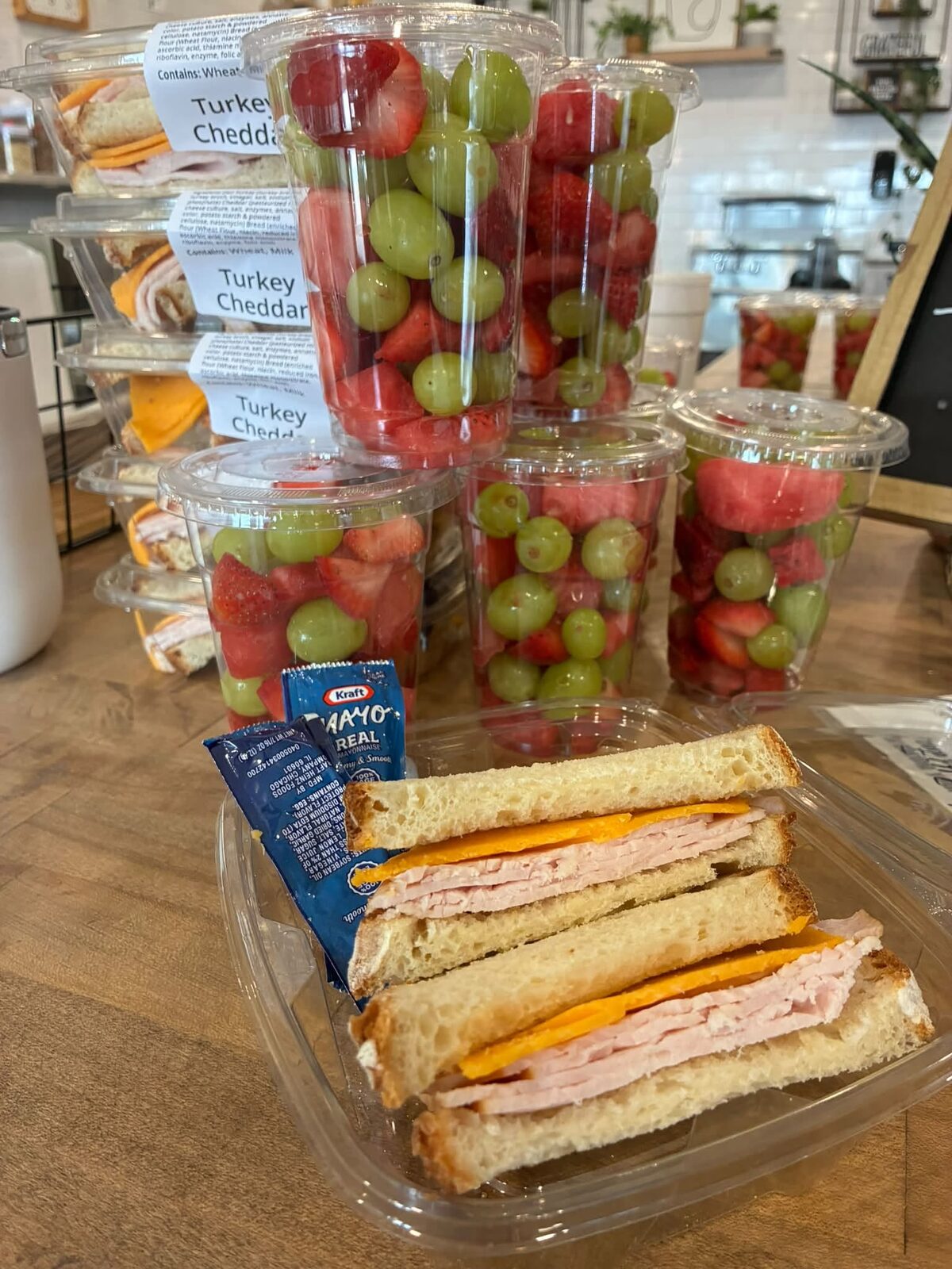 Fruit cups of grapes and strawberries with a sandwich in the display case