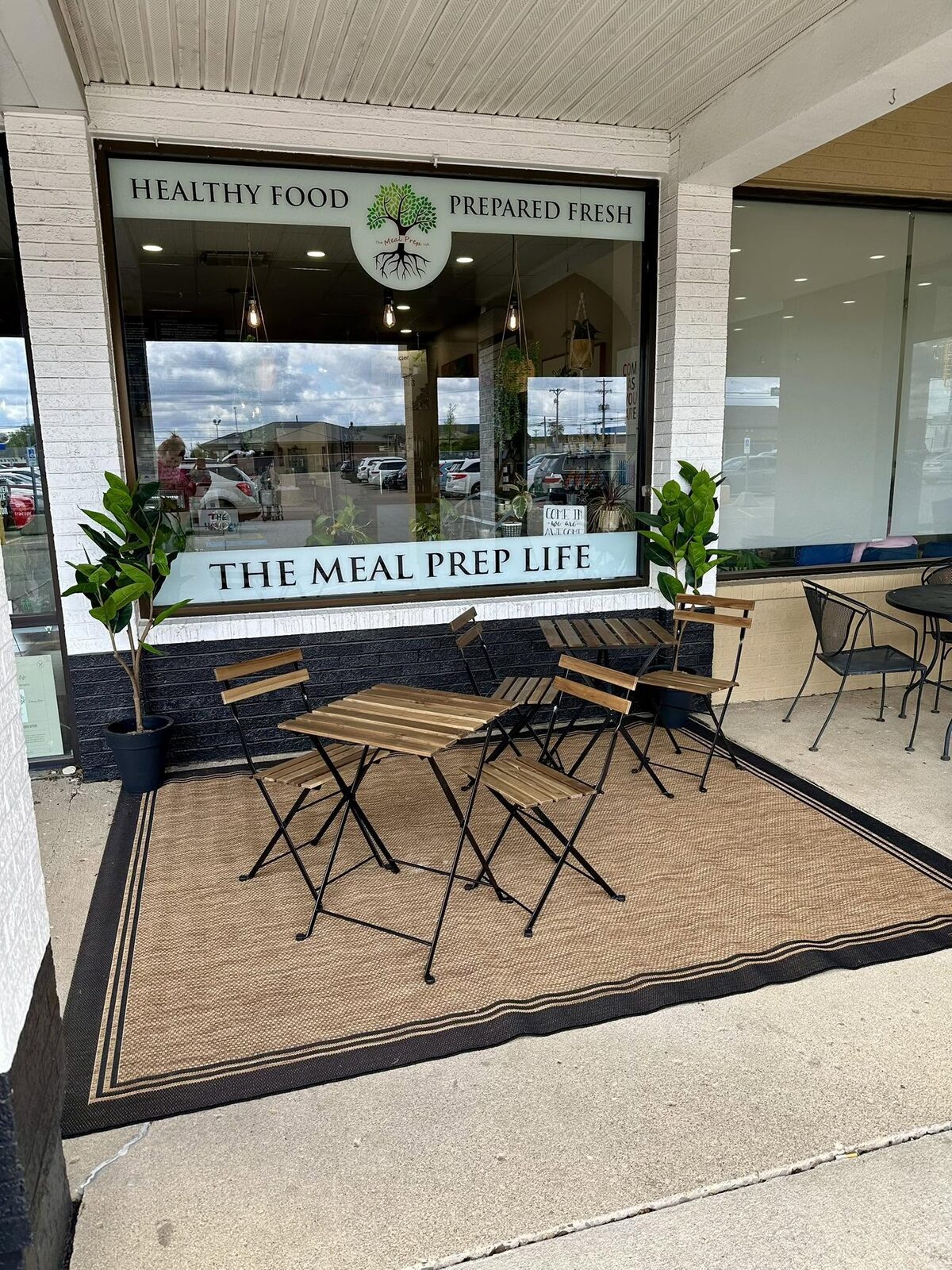 The Meal Prep Life storefront with café tables, next door
