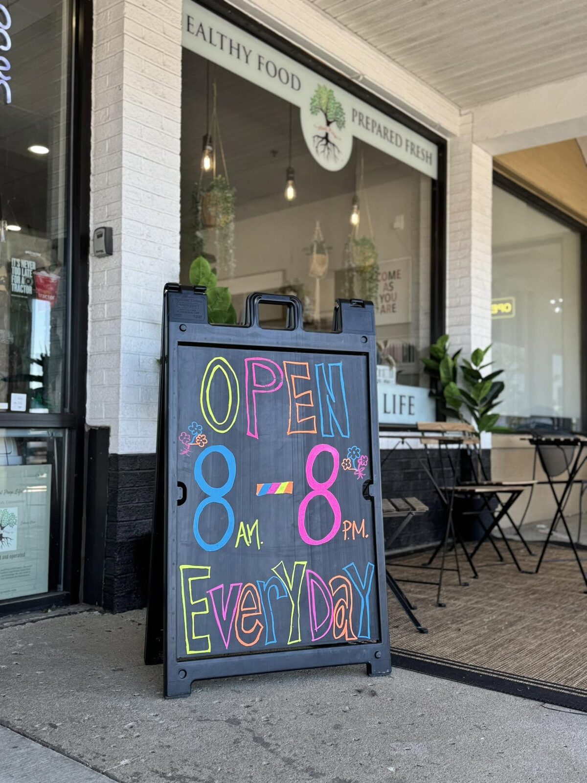 The shop door in Sidney Towne Center with the chalk board reading Open 8 AM to 8 PM every day