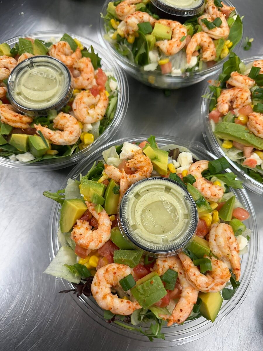 Shrimp salads in the cooler tubs with avocado, corn and a pot of dressing