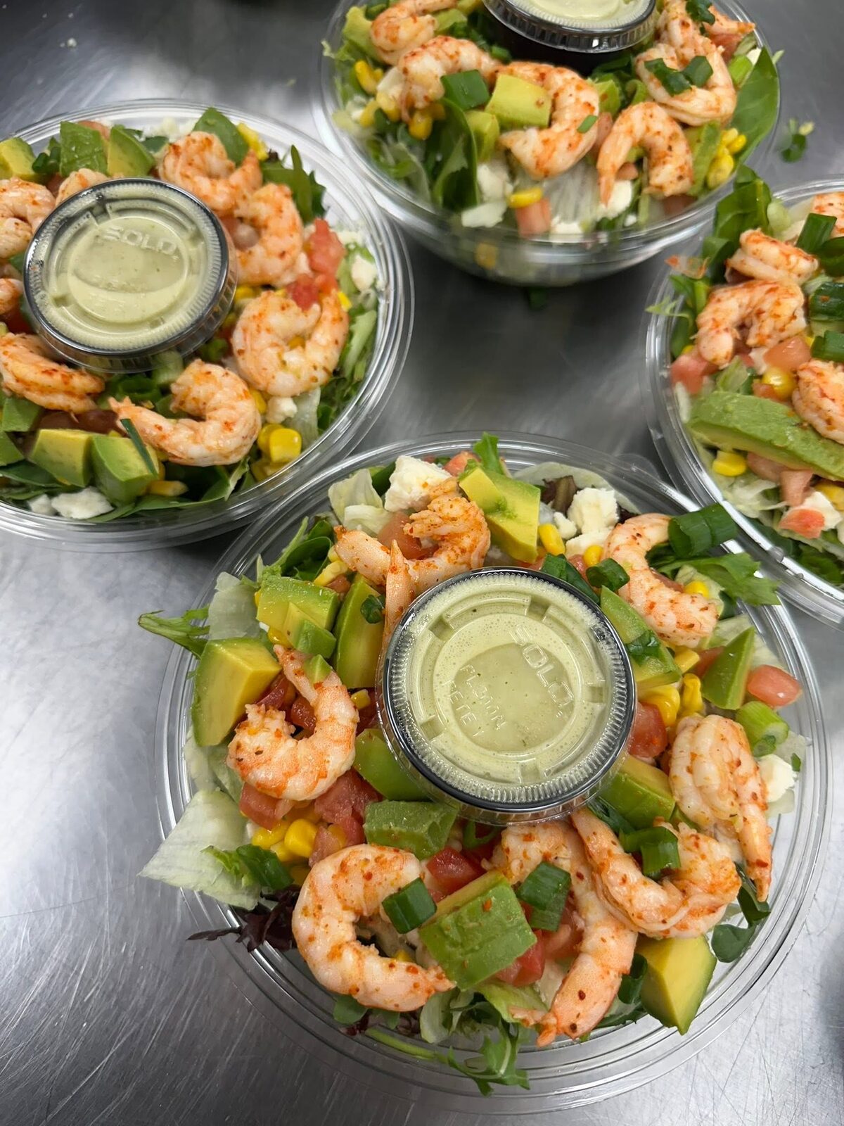 Shrimp salads with avocado and a dressing cup, from above