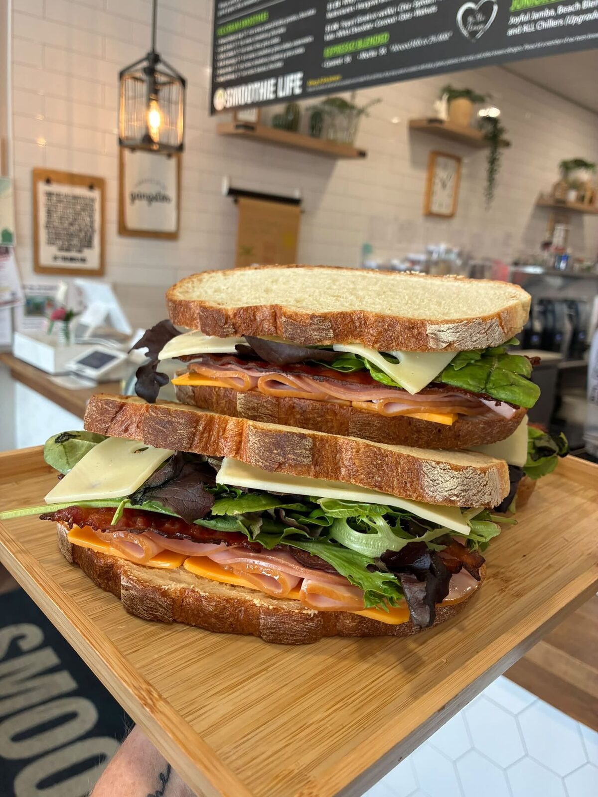 A stacked turkey sandwich on a wooden board at the counter
