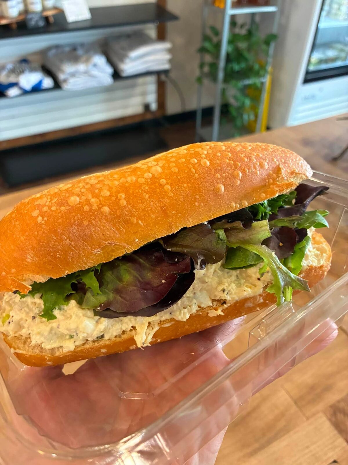 A sub with greens held up at the counter