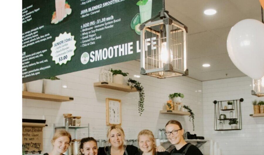 Five of the team lined up behind the counter under the Smoothie Life sign