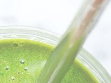 A green smoothie in a glass with a straw, photographed from above at the shop