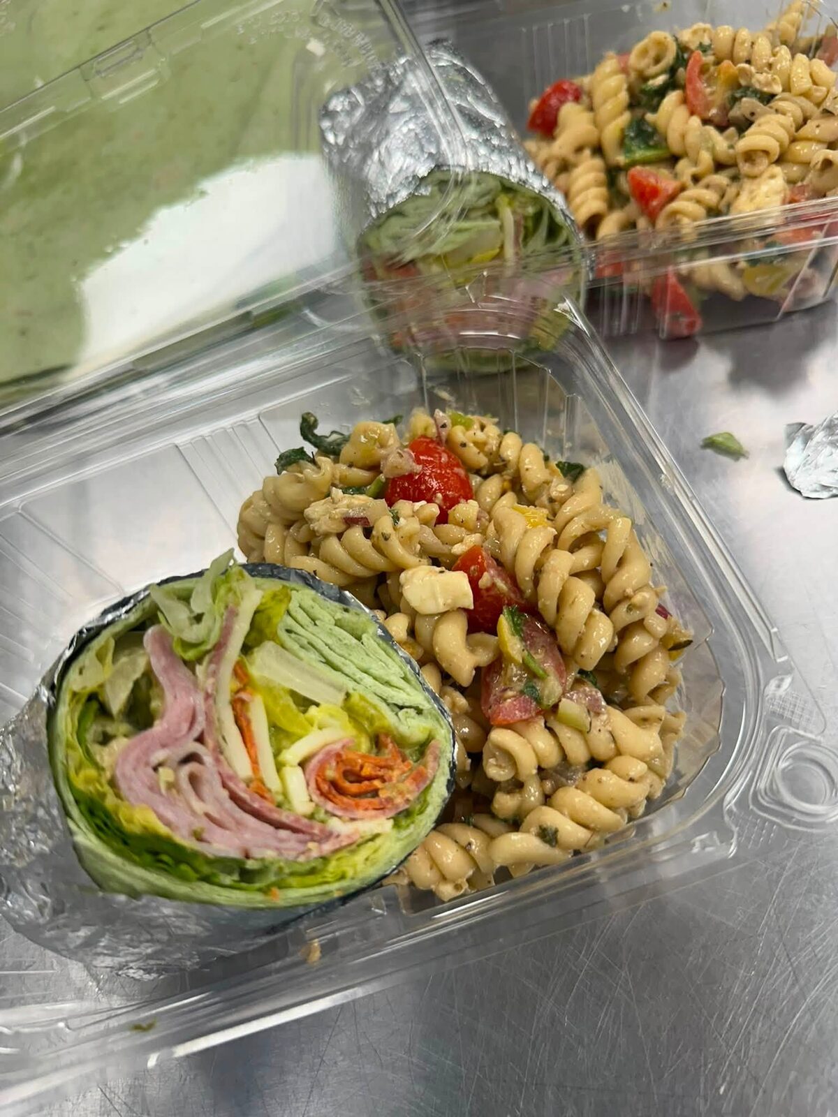 A wrap and a pasta salad in a to-go box
