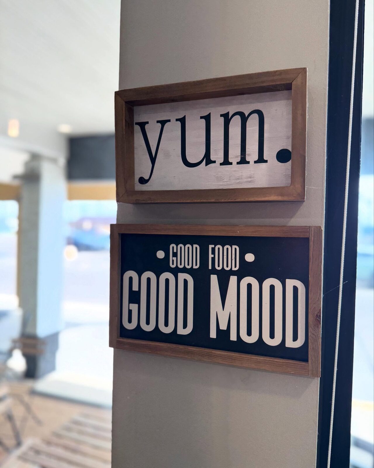 Two framed signs on the wall: yum, and good food good mood